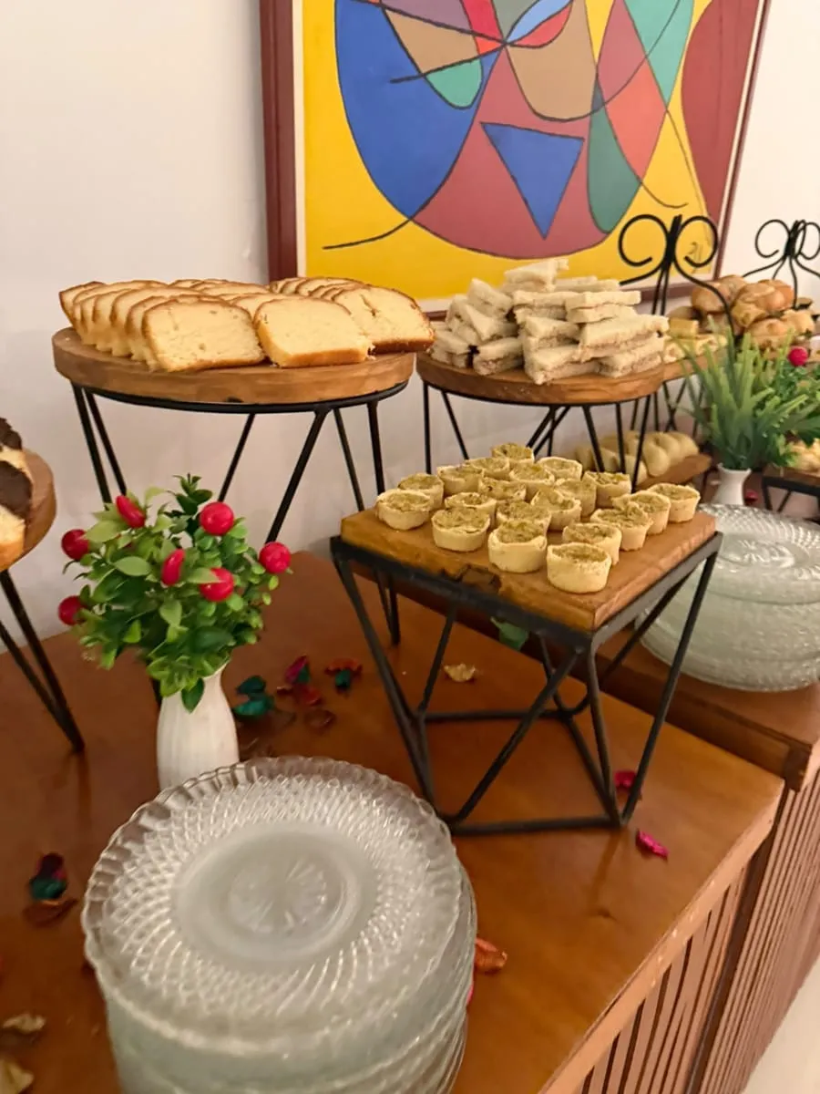 Fatias de bolo, sanduíches e mini tortinhas em mesa decorada com flores — evento corporativo do Buffet Big House