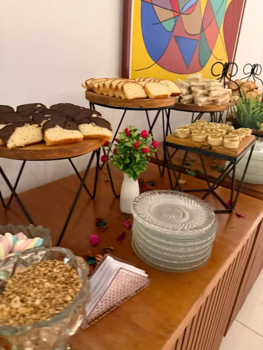 Bolos fatiados e sanduíches em expositores, ao lado de pratos de vidro — evento corporativo do Buffet Big House